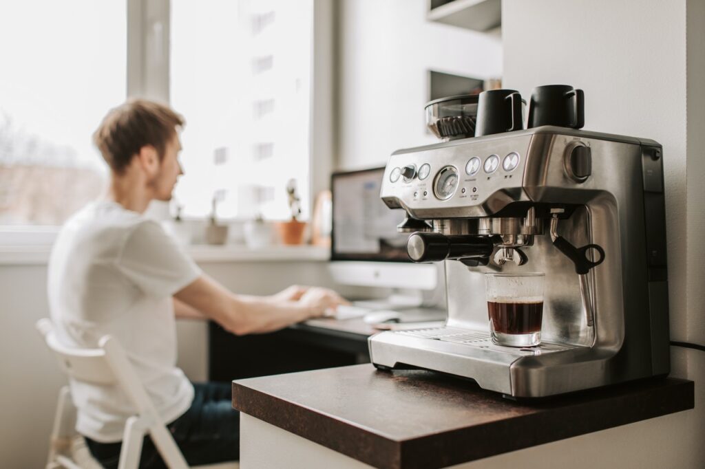 Advanced coffee making machine, with digital nomad guest in the background